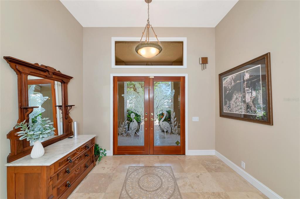 An entryway features double glass doors with etched designs, a marble-topped dresser, and tile flooring — 1495 LANDVIEW LANE, OSPREY, FL