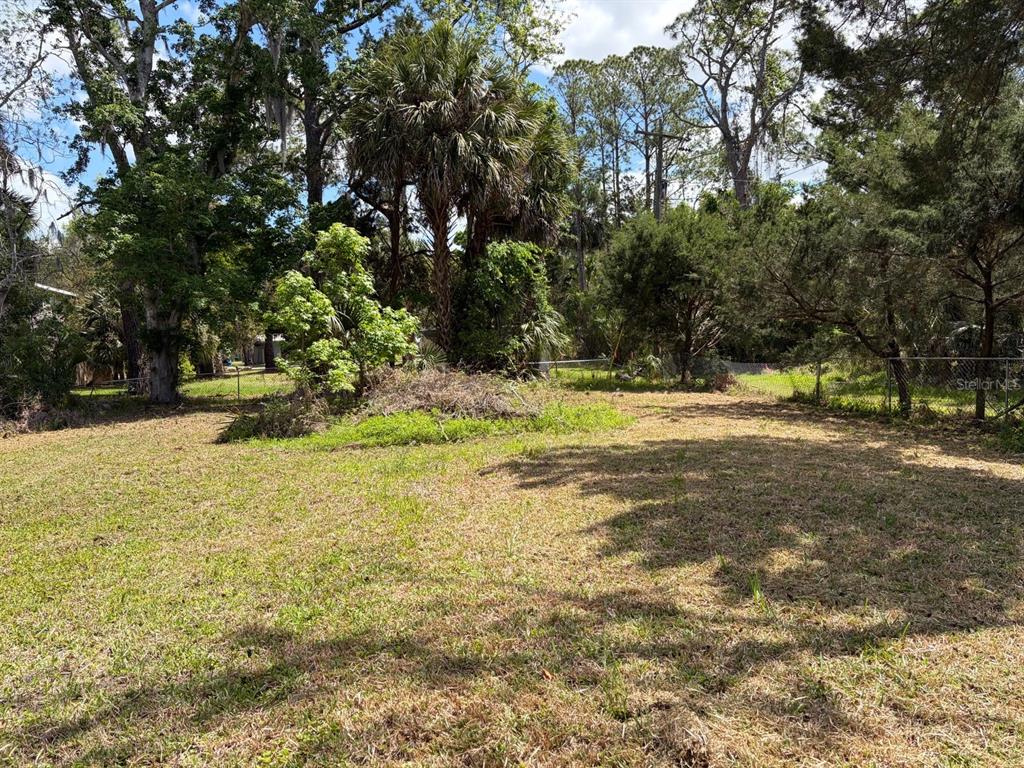 A grassy, partially wooded vacant lot features a pile of brush and a chain-link fence — 38 65TH STREET, YANKEETOWN, FL