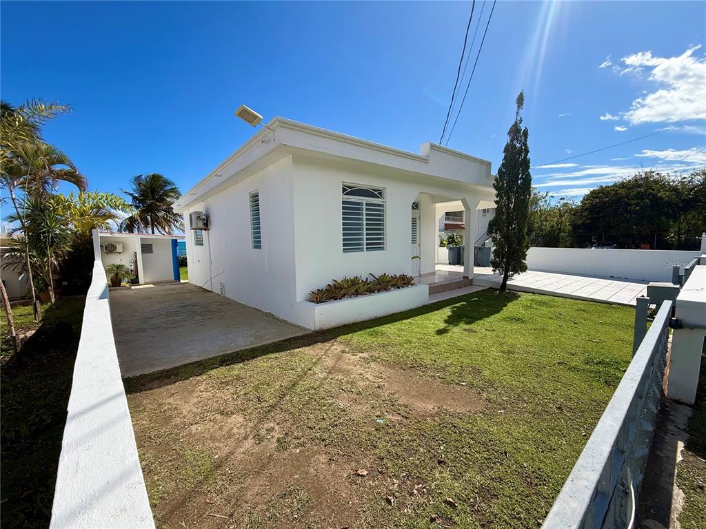 A white single-story house with a lawn, driveway, and a low wall in front — Carr#3 BEACH FRONT HOUSE AVENUE, PATILLAS, PR