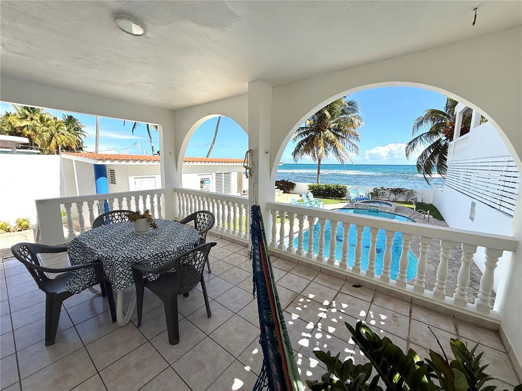 A covered patio with a dining set and hammock overlooks a swimming pool and ocean — Carr#3 BEACH FRONT HOUSE AVENUE, PATILLAS, PR