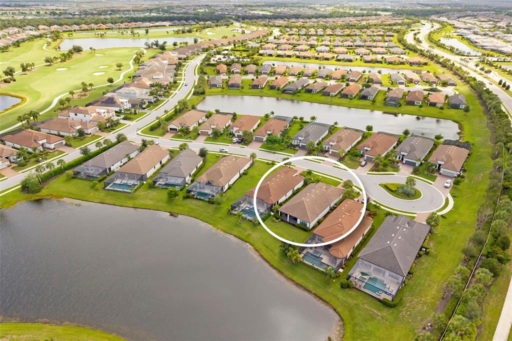 An aerial view shows a residential neighborhood with houses, swimming pools, and a large lake — 4730 SARCA COURT, BRADENTON, FL