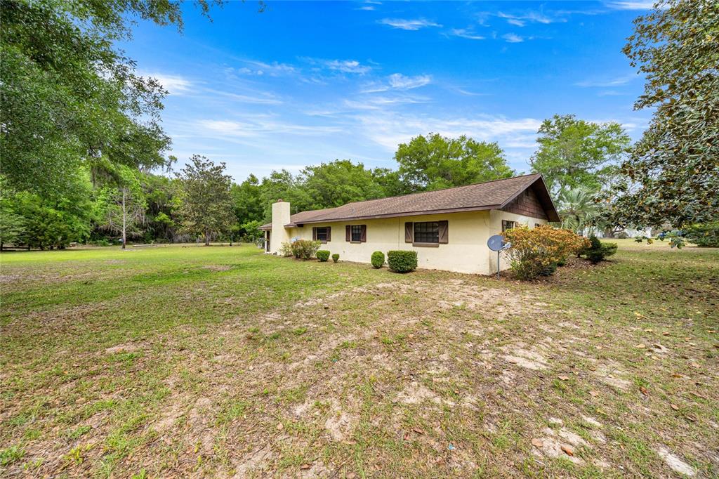A single-story house with a beige exterior and a brown roof sits on a lawn — 12882 SE 78TH TERRACE, SUMMERFIELD, FL