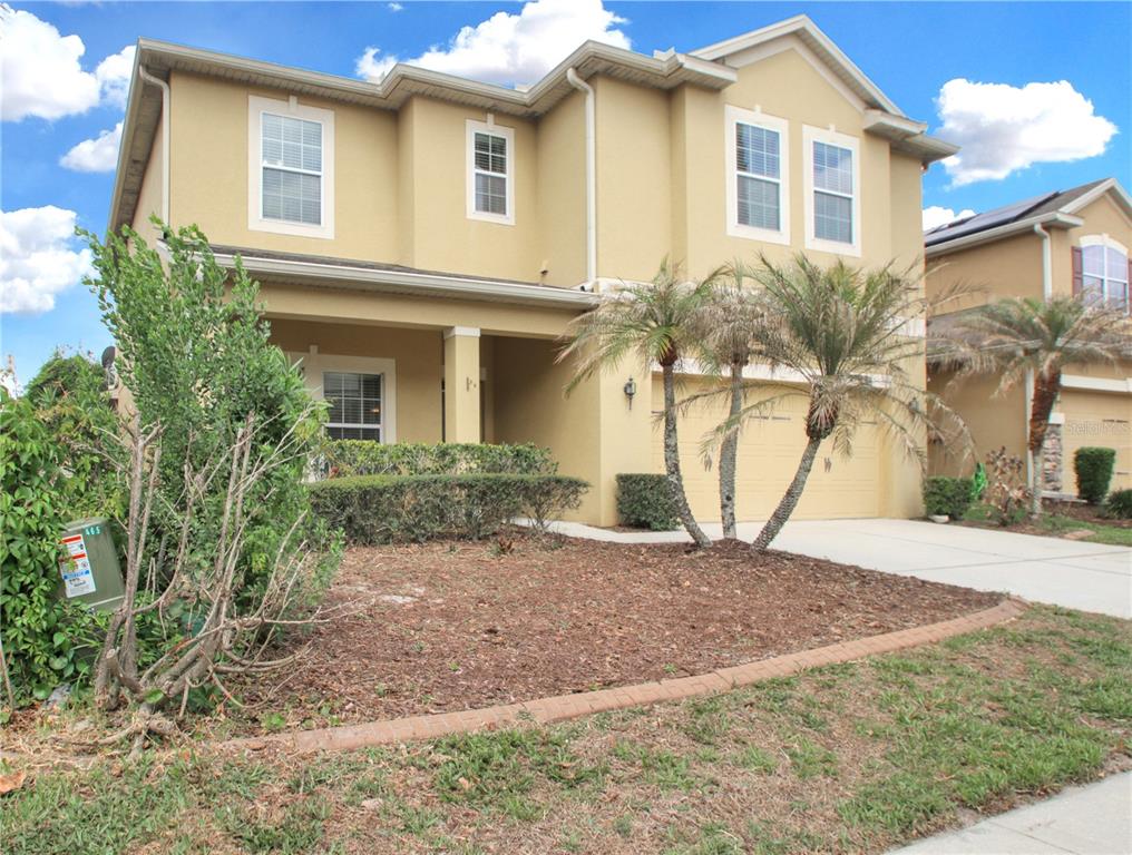 A two-story tan house with a two-car garage and palm trees in the front yard — 9009 VICKROY TERRACE, OVIEDO, FL