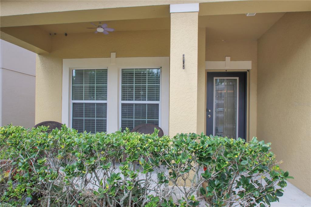 A covered front porch features a dark door, two windows, and a hedge in front — 9009 VICKROY TERRACE, OVIEDO, FL