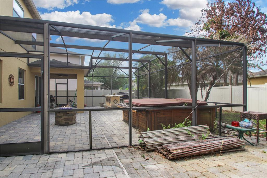 A screened-in patio features a stone fire pit, a hot tub, and a bar area — 9009 VICKROY TERRACE, OVIEDO, FL