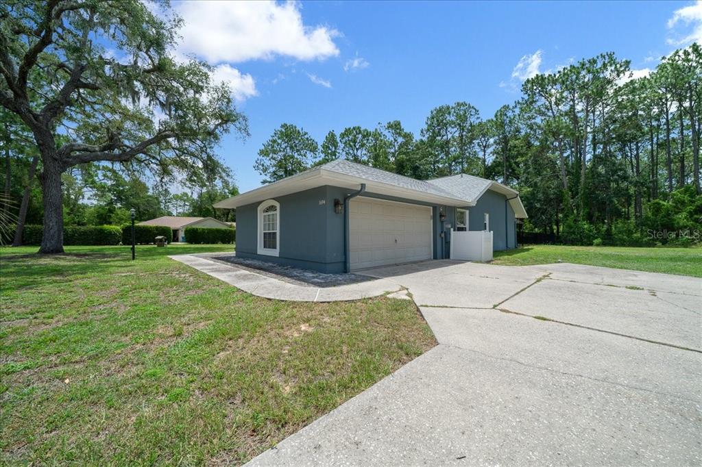 A gray house with a two-car garage and a concrete driveway sits on a grassy lot — 1694 W PEARSON STREET, HERNANDO, FL
