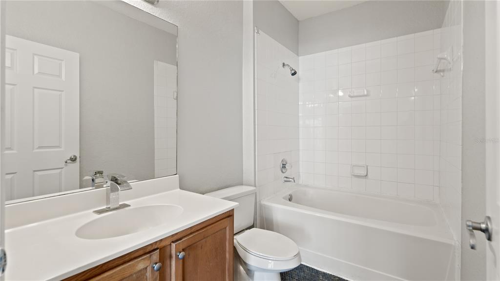 A bathroom features a wooden vanity, a white sink, a toilet, and a tiled tub-shower — 2586 GRAND CENTRAL PARKWAY UNIT 3, ORLANDO, FL