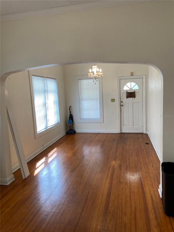 An empty room with hardwood floors, an arched doorway, and a white front door — 108 S WILLOW AVENUE, TAMPA, FL