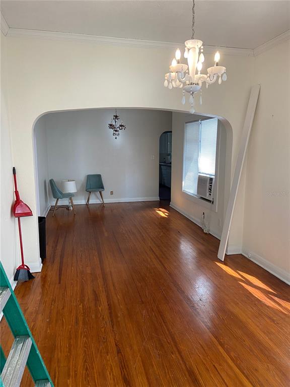An interior view shows a living area with hardwood floors, a chandelier, and an arched doorway — 108 S WILLOW AVENUE, TAMPA, FL
