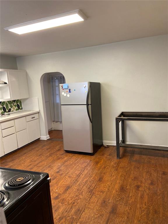A kitchen features white cabinets, a stainless steel refrigerator, and a metal table on wood floors — 108 S WILLOW AVENUE, TAMPA, FL