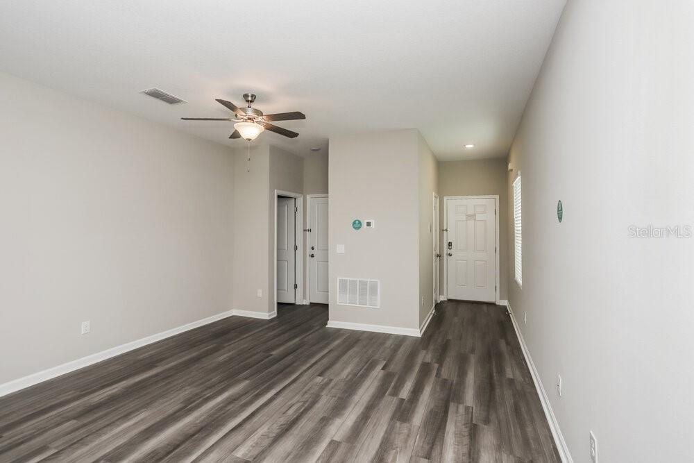 An empty room with gray wood-look flooring, light walls, a ceiling fan, and white doors — 966 KELLY FERN LOOP, RUSKIN, FL