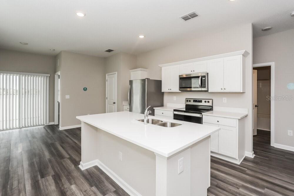 A modern kitchen features a white island, stainless steel appliances, and light-colored cabinetry — 966 KELLY FERN LOOP, RUSKIN, FL