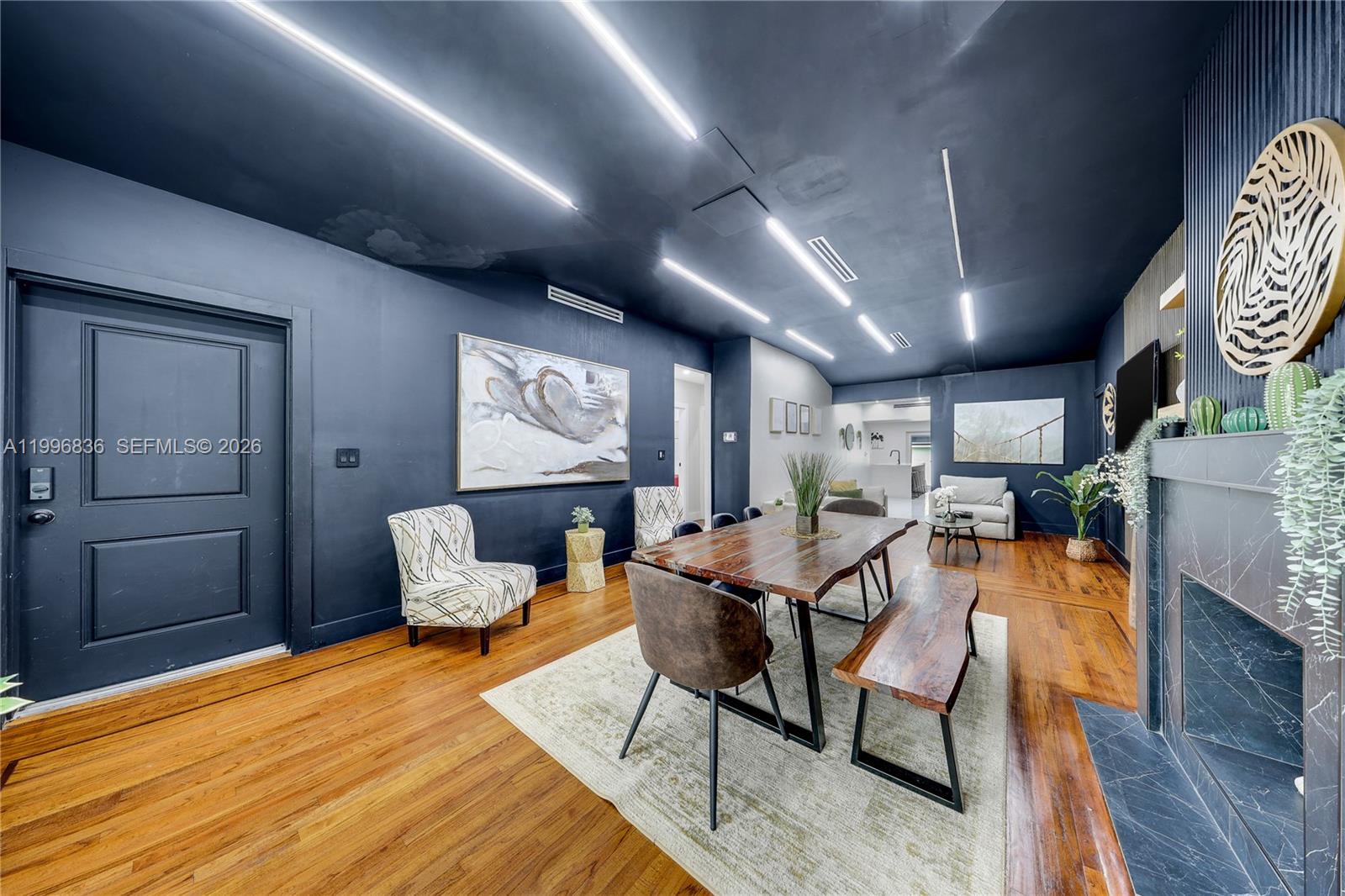 A dining room features dark blue walls, a live-edge wood table, and linear ceiling lights — 2612 SW 12th St, Miami FL 33135, MIAMI, FL