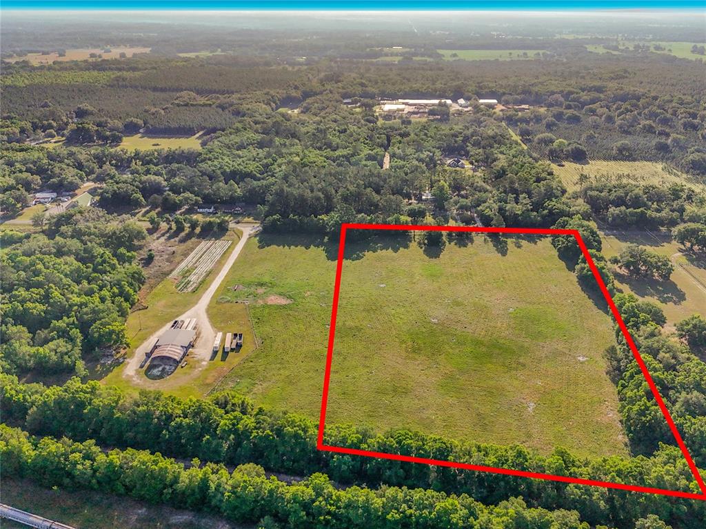 An aerial view shows a large, rectangular grassy field outlined in red next to farm buildings — TBD NE 195TH AVENUE, WILLISTON, FL