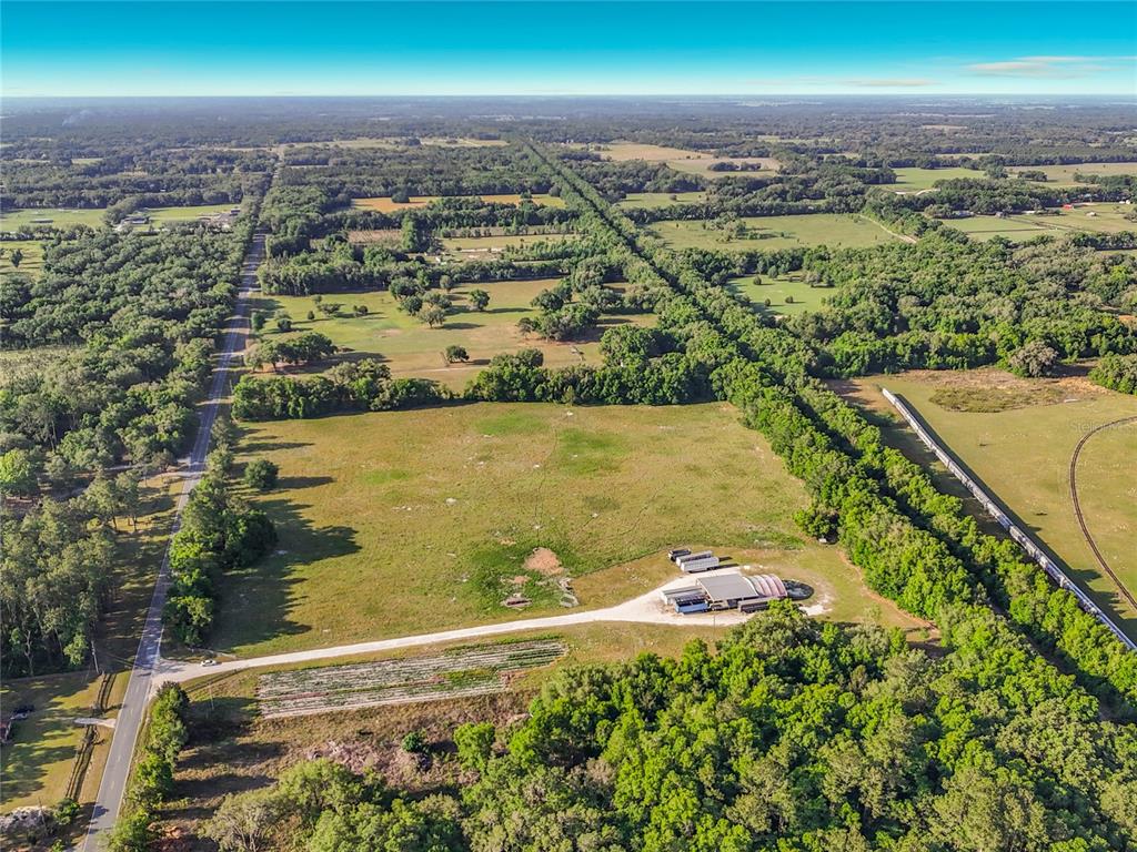An aerial view shows a large, grassy rural property with a building and a road — TBD NE 195TH AVENUE, WILLISTON, FL