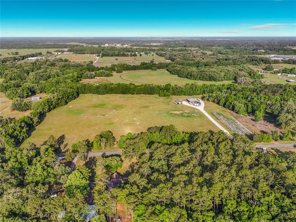 An aerial view shows a large grassy field, a barn, and a house among trees — TBD NE 195TH AVENUE, WILLISTON, FL