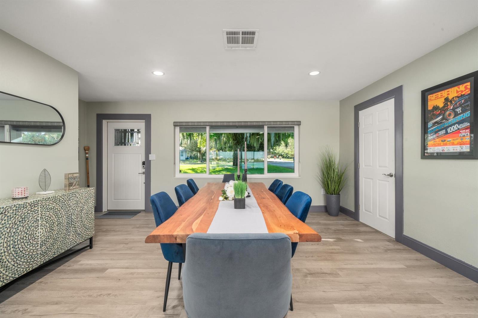 A dining room features a live-edge wood table, blue velvet chairs, and light wood flooring — 1622 W Dinner Lake Drive, Sebring FL 33870, SEBRING, FL