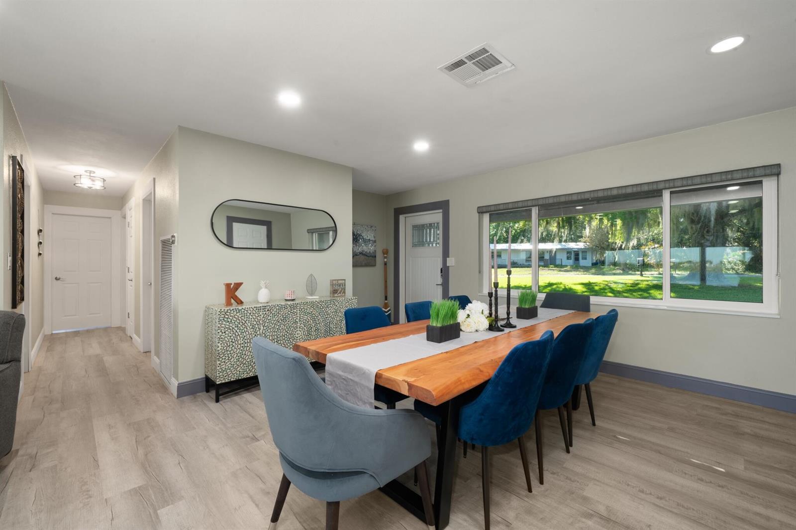 A dining room features a live-edge wood table, blue velvet chairs, and a patterned sideboard — 1622 W Dinner Lake Drive, Sebring FL 33870, SEBRING, FL