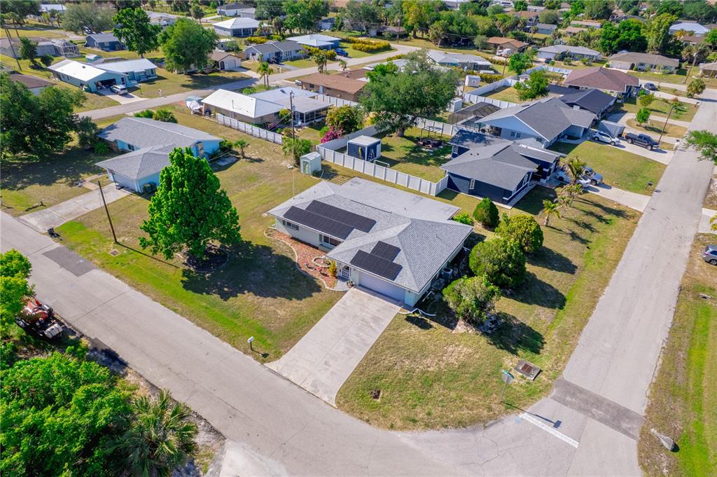 An aerial view shows a suburban house with solar panels on its roof and a driveway — 22158 RIVERHEAD AVENUE, PORT CHARLOTTE, FL