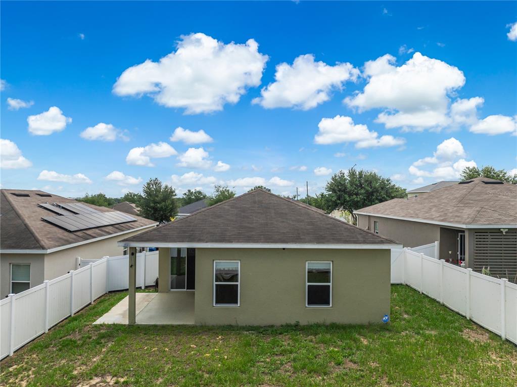 The rear exterior of a single-story house features a small covered patio and fenced yard — 125 TANAGER STREET, HAINES CITY, FL