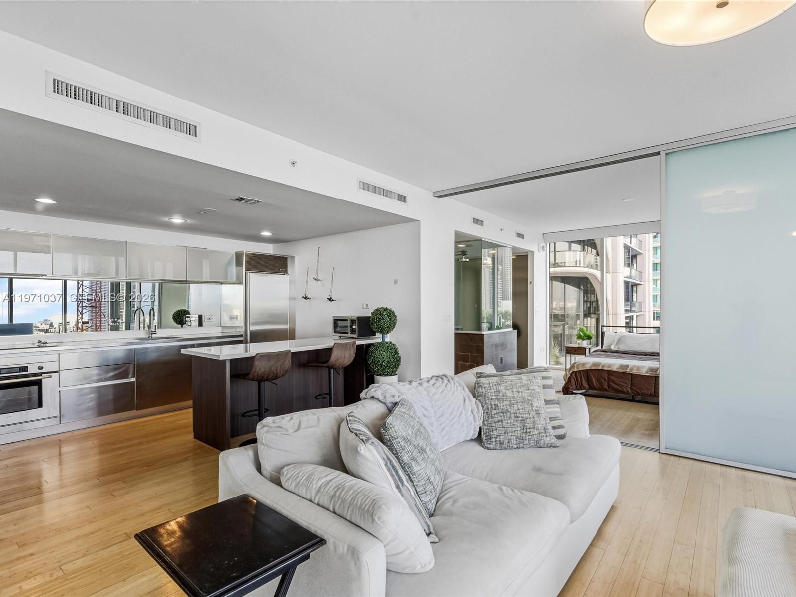 A modern apartment features an open kitchen, living area, and a bedroom behind sliding doors — 1040 Biscayne Blvd # 1107, Miami FL 33132, MIAMI, FL