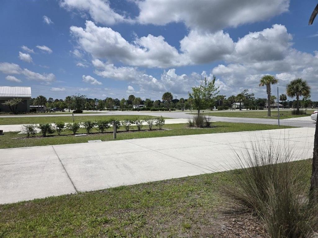 A concrete driveway leads to a grassy area with palm trees under a cloudy sky — HIGHWAY 630  E UNIT 44, LAKE WALES, FL