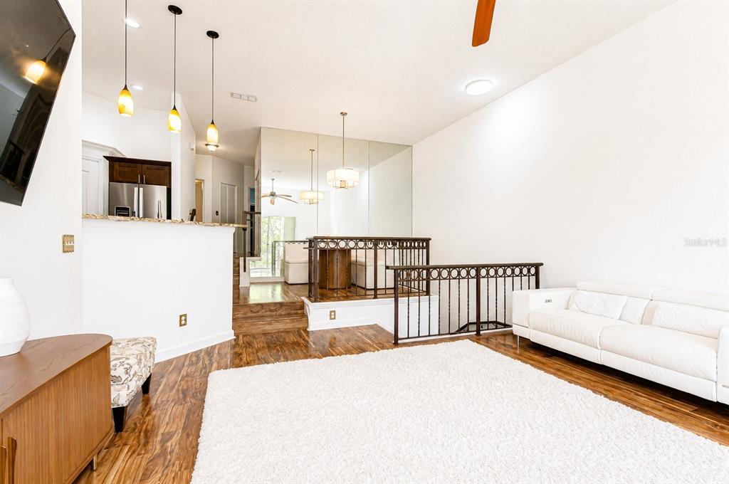 A living room features hardwood floors, a white sofa, and a raised dining area — 609 TROPICAL BREEZE WAY UNIT 609, TAMPA, FL