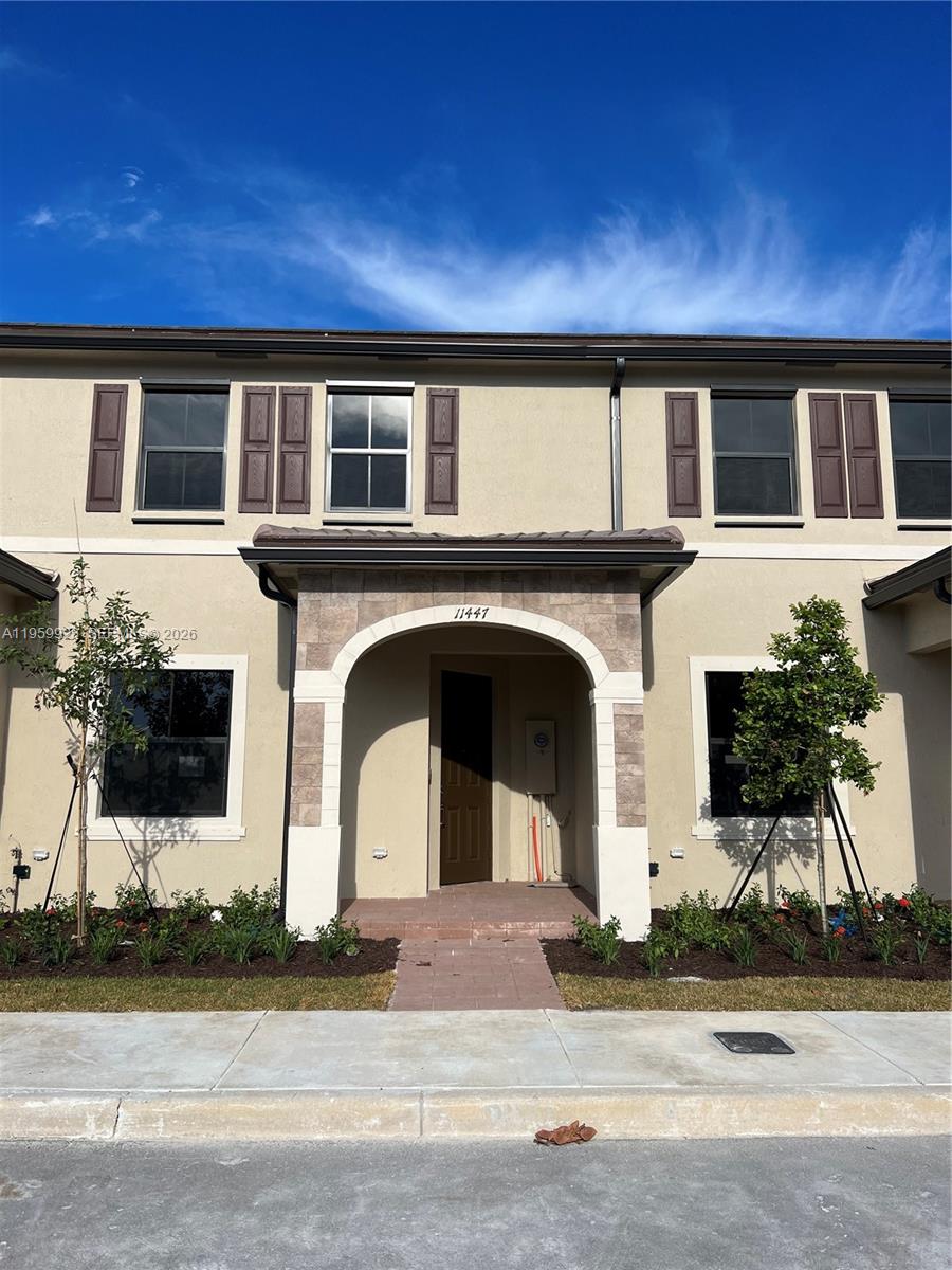 A two-story townhouse exterior features a stone-accented arched entryway and brown shutters — 11447 W 34th Ct, Hialeah FL 33018, HIALEAH, FL