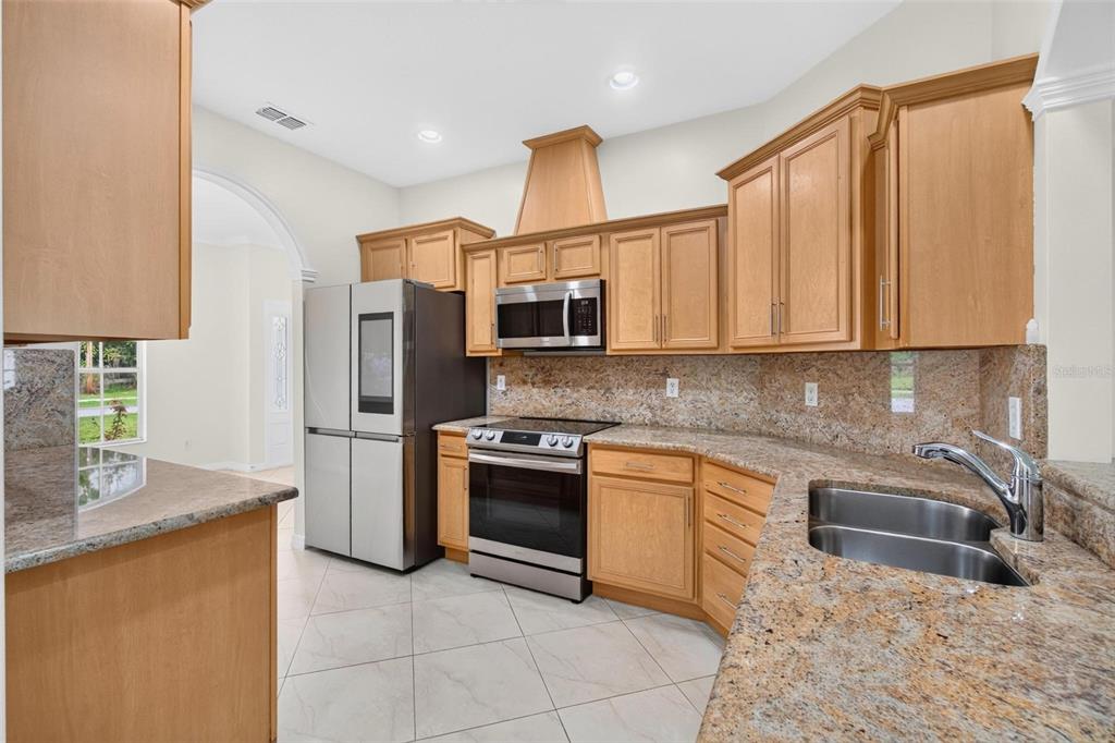 A kitchen with light wood cabinets, granite countertops, stainless steel appliances, and tile flooring — 6026 113TH AVENUE N, PINELLAS PARK, FL
