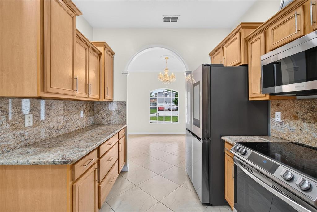A kitchen with light wood cabinets, granite countertops, stainless steel appliances, and a tiled floor — 6026 113TH AVENUE N, PINELLAS PARK, FL