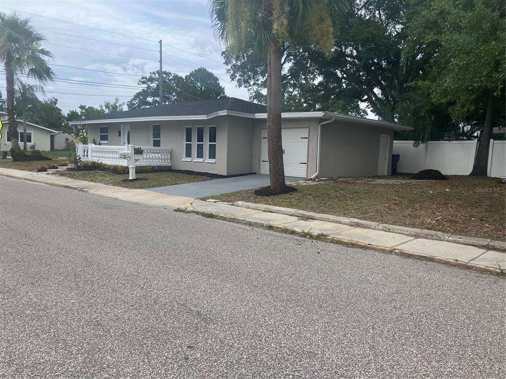 A single-story house with a gray exterior, a white fence, and an attached garage — 601 BANANA STREET, TARPON SPRINGS, FL