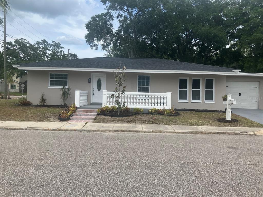 A single-story house with a beige exterior, white front door, and a white balustrade railing — 601 BANANA STREET, TARPON SPRINGS, FL