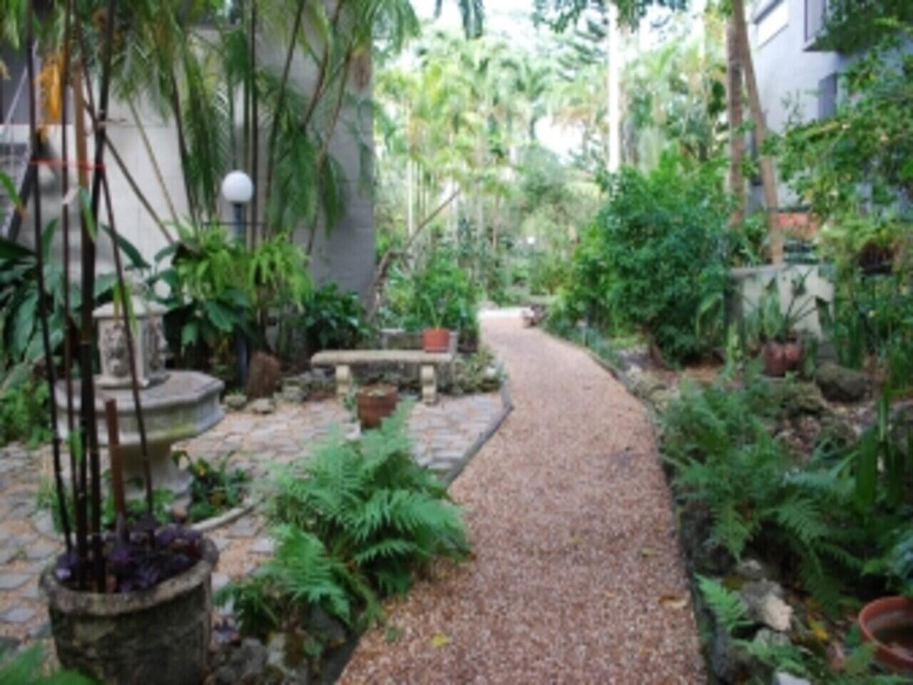 A gravel path winds through a lush garden with a stone fountain and a bench — 1000 NW N River Drive # 16, Miami FL 33136, MIAMI, FL