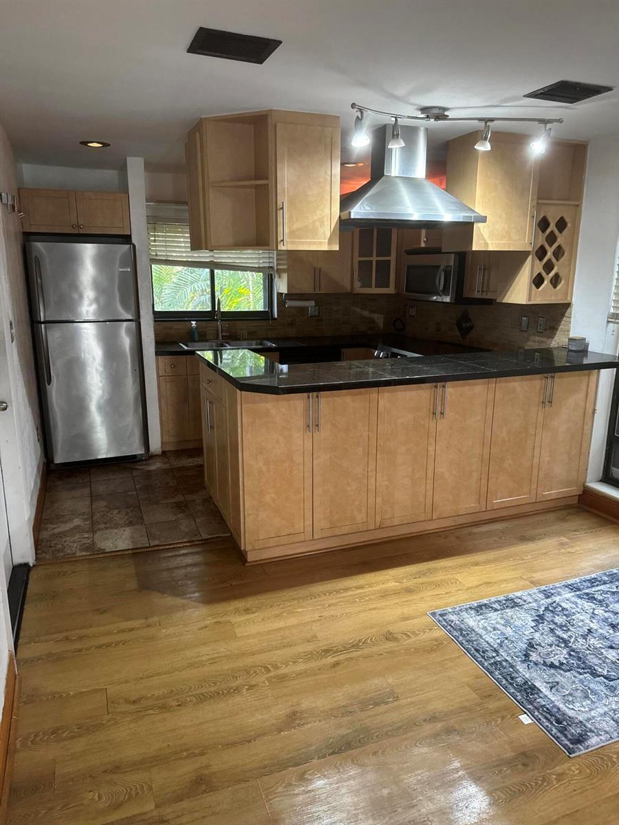 A kitchen with light wood cabinets, black countertops, stainless steel appliances, and wood flooring — 1000 NW N River Drive # 16, Miami FL 33136, MIAMI, FL