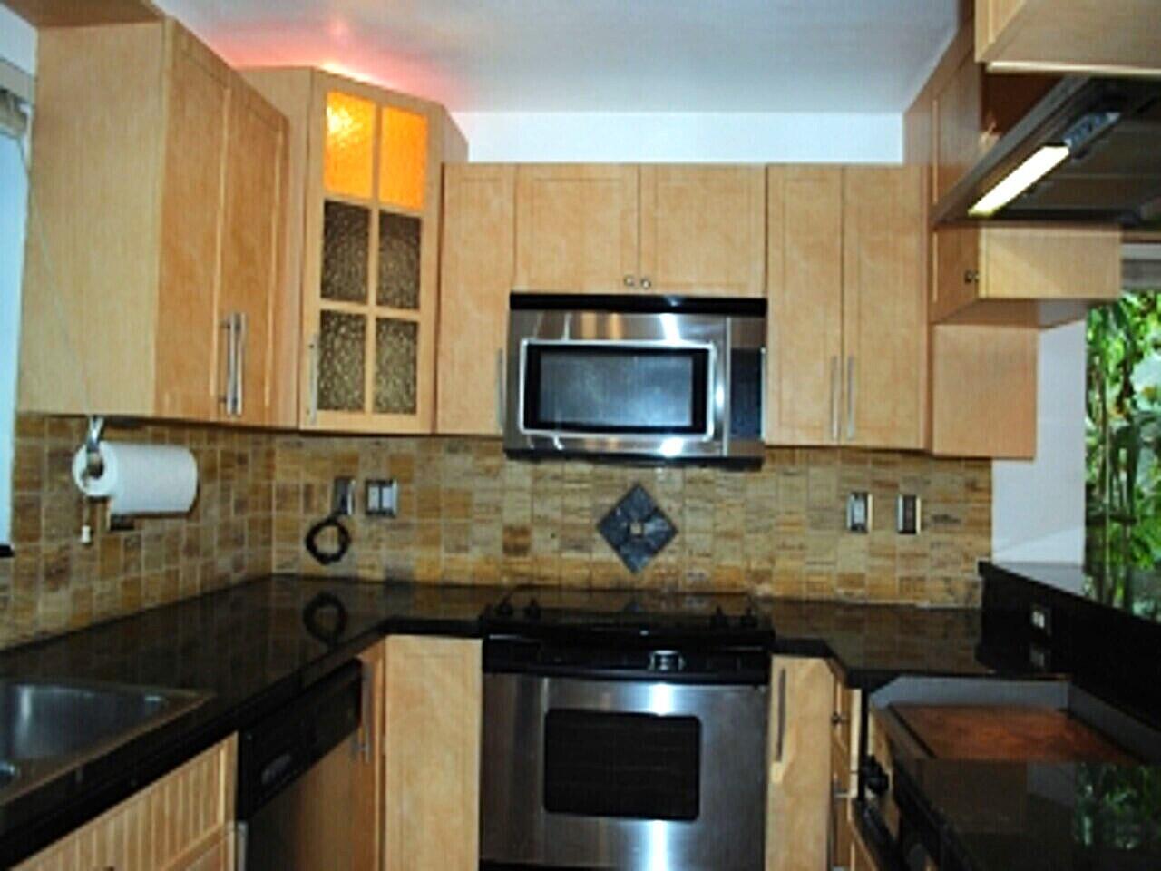 A kitchen features light wood cabinets, black countertops, stainless steel appliances, and a tiled backsplash — 1000 NW N River Drive # 16, Miami FL 33136, MIAMI, FL