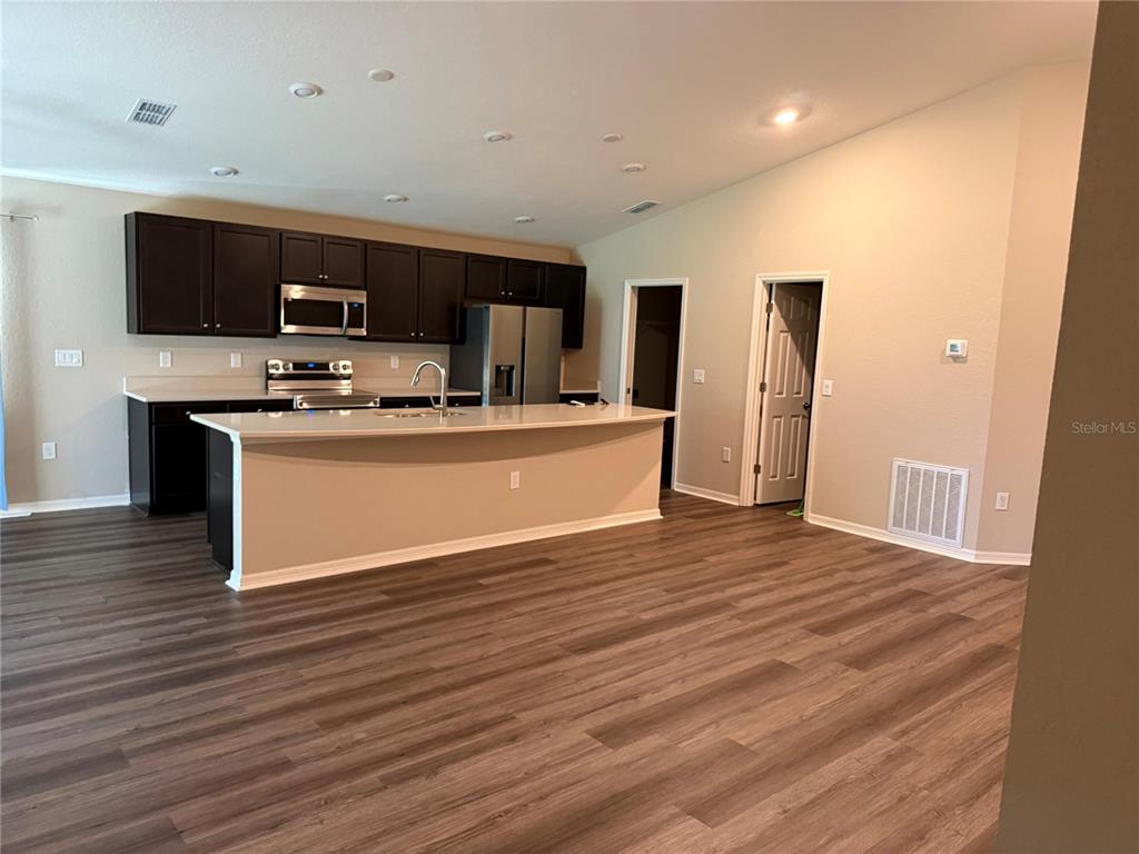 A kitchen with dark cabinets, stainless steel appliances, and a large island on wood flooring — 615 BENTLEY NORTH DRIVE, AUBURNDALE, FL