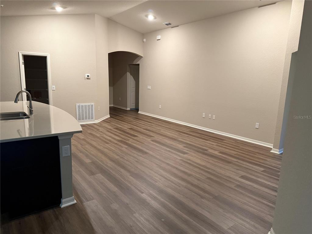 An open-concept living area features light-colored walls, wood-look flooring, and a kitchen island — 615 BENTLEY NORTH DRIVE, AUBURNDALE, FL