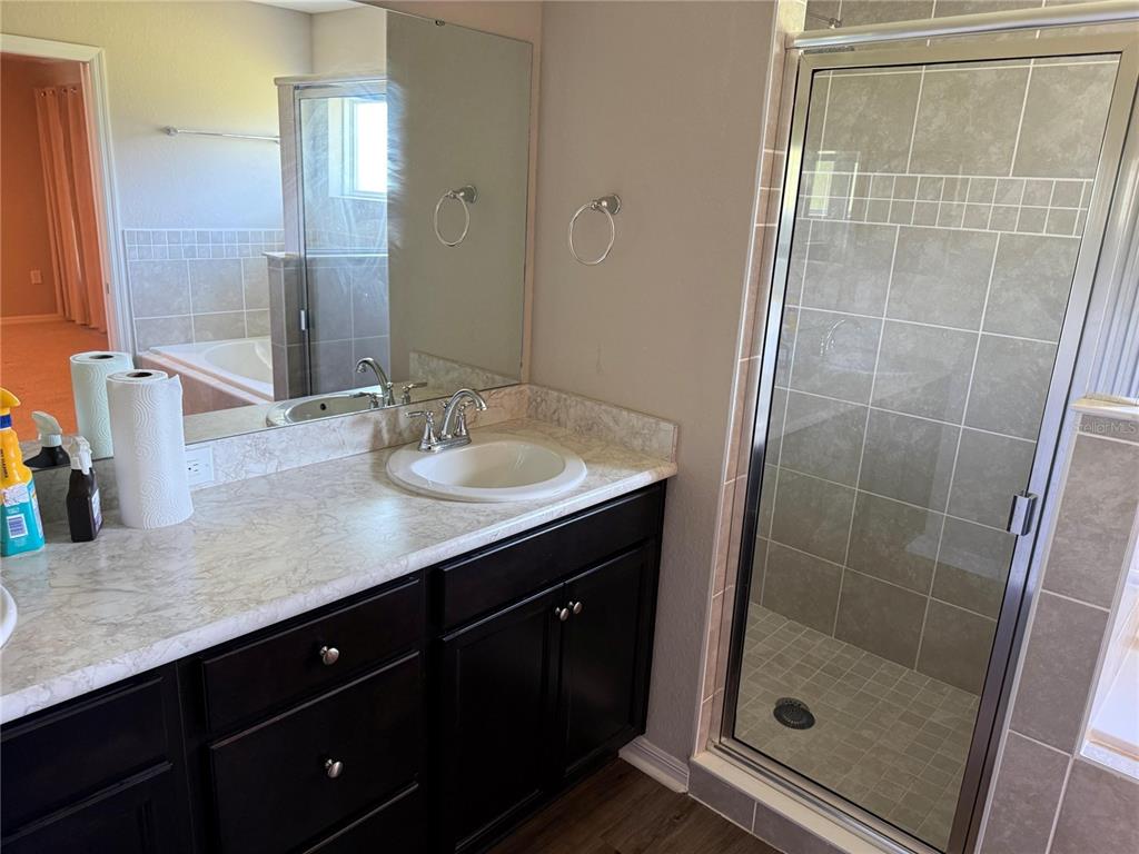 A bathroom features a dark wood vanity with a light countertop and a glass-enclosed shower — 615 BENTLEY NORTH DRIVE, AUBURNDALE, FL