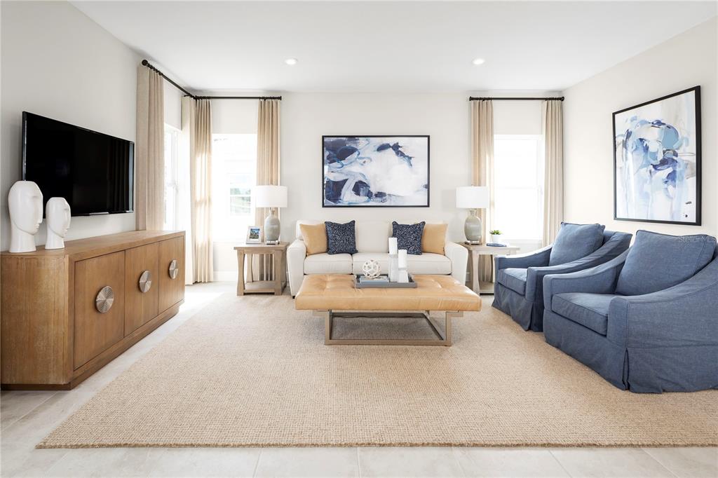 A living room features a beige sofa, two blue armchairs, a leather ottoman, and a television — 2437 WHITE LADYFISH ROAD, WIMAUMA, FL