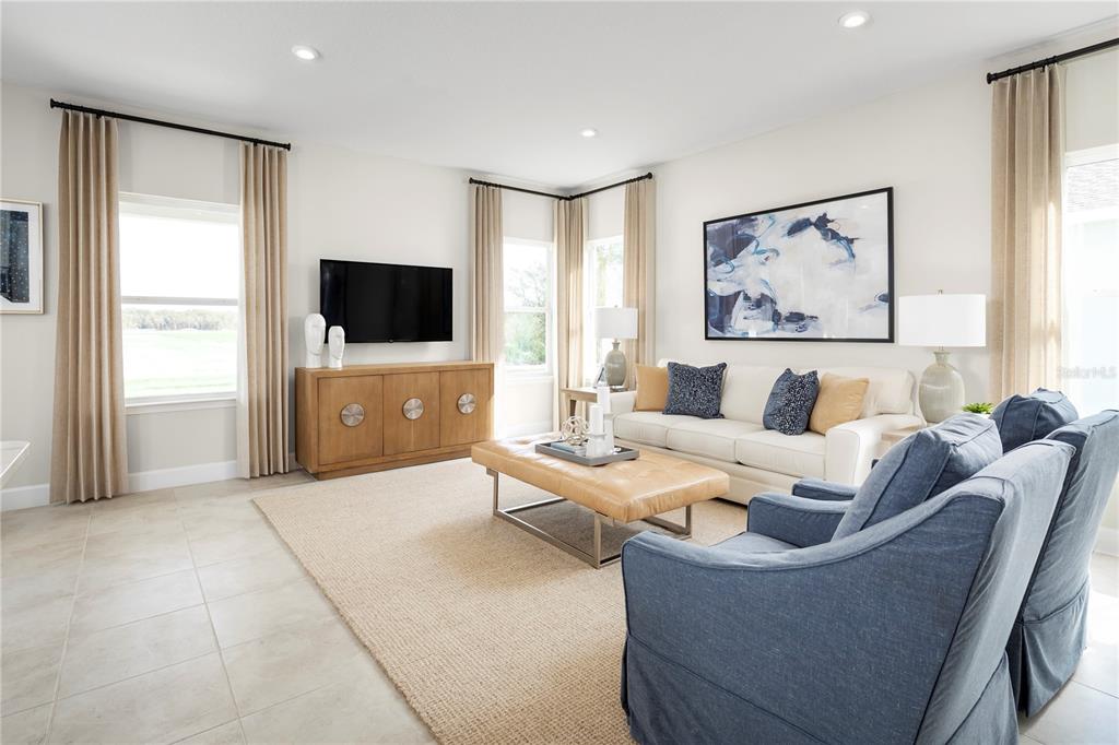A living room features a white sofa, blue armchairs, a tan ottoman, and a television — 2437 WHITE LADYFISH ROAD, WIMAUMA, FL