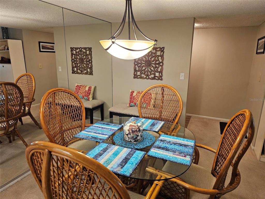 A dining room features a glass-topped table with wicker chairs and a mirrored wall — 4119 61ST AVENUE TERRACE W UNIT 303, BRADENTON, FL