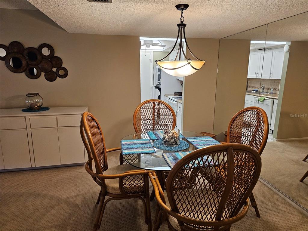 A dining area features a glass-topped table with four wicker chairs under a pendant light — 4119 61ST AVENUE TERRACE W UNIT 303, BRADENTON, FL
