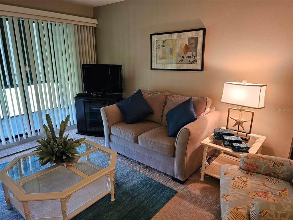 A living room features a loveseat, a glass-top coffee table, and a side table with a lamp — 4119 61ST AVENUE TERRACE W UNIT 303, BRADENTON, FL