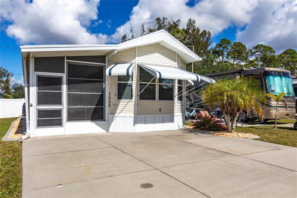 A light-colored mobile home with a screened-in porch and a concrete driveway — 1604 N MANATEE LOOP, PUNTA GORDA, FL