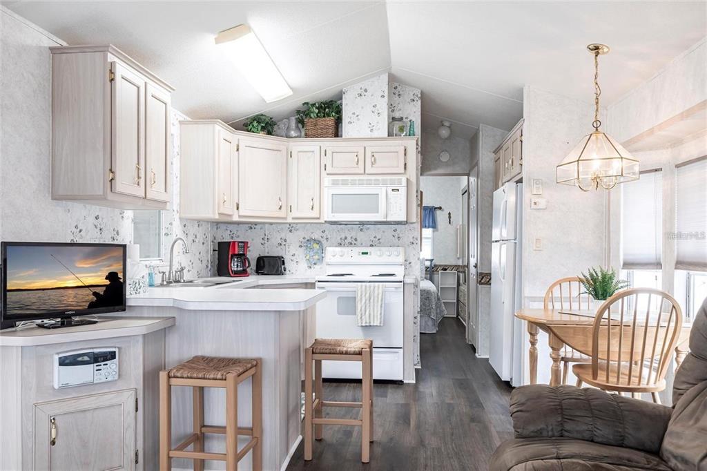 A kitchen and dining area with light wood cabinets, white appliances, and floral wallpaper — 1604 N MANATEE LOOP, PUNTA GORDA, FL