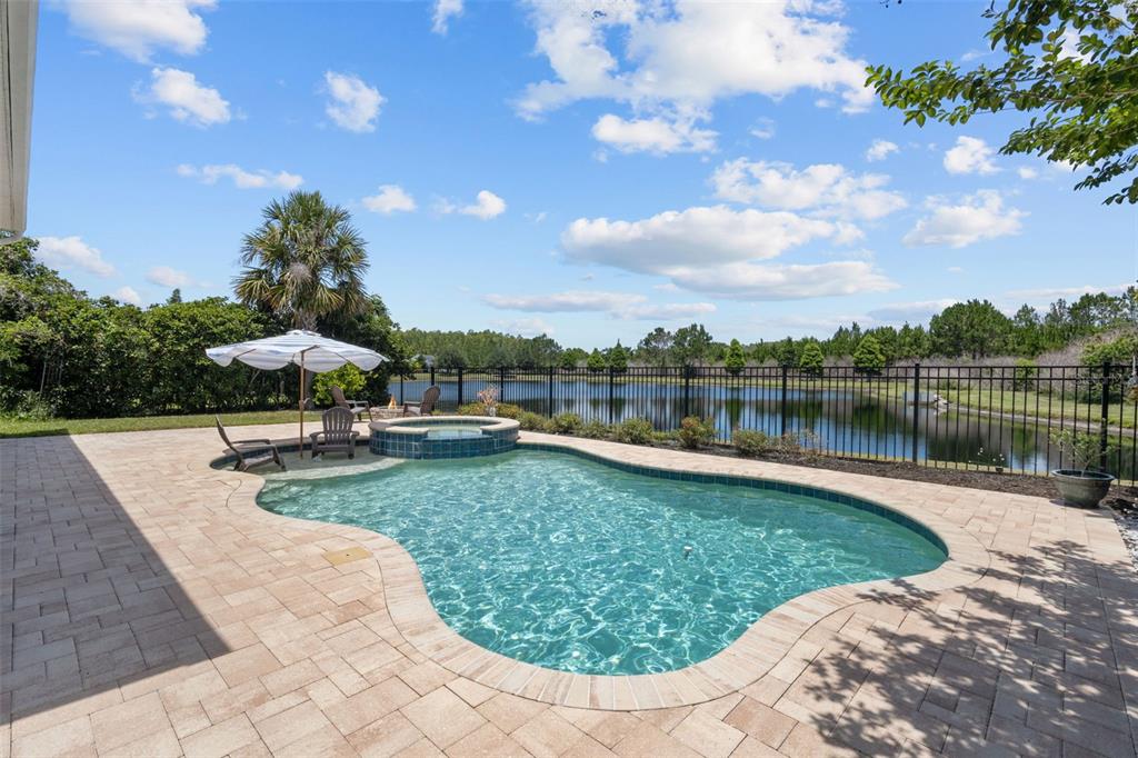 A backyard features a swimming pool with an attached spa, patio, and lake view — 2903 LONG BOW WAY, ODESSA, FL