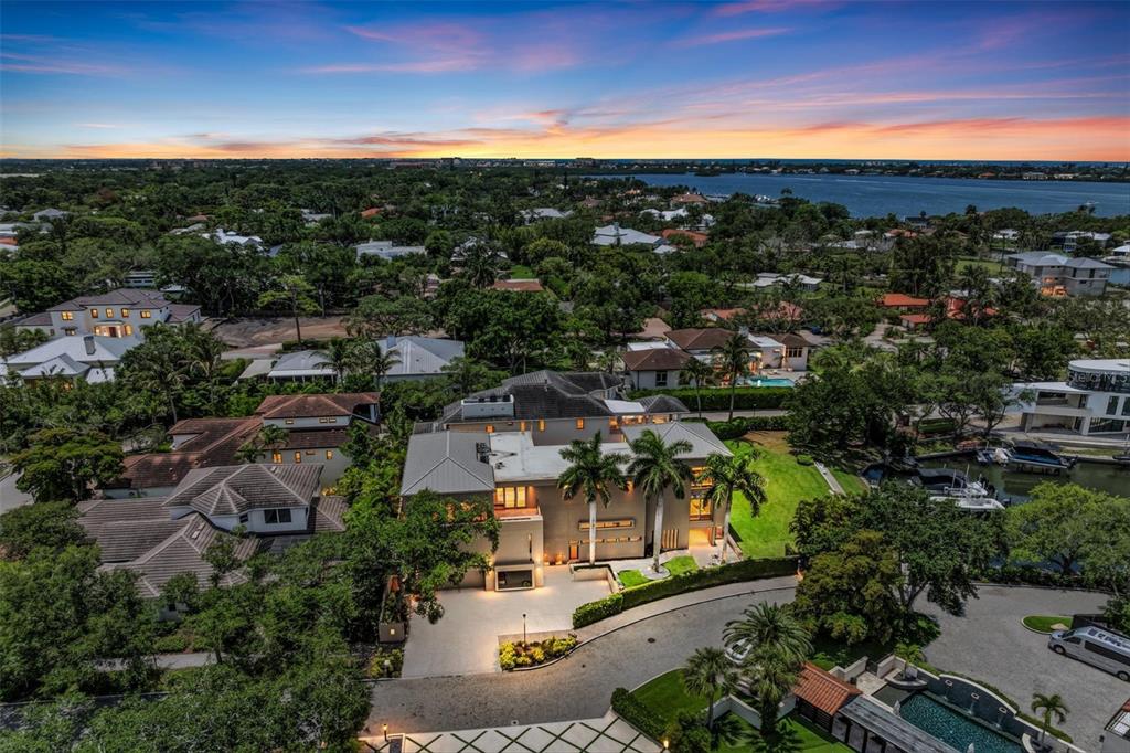 A modern, multi-story tan house with palm trees and a paved driveway at dusk — 1404 KENILWORTH STREET, SARASOTA, FL