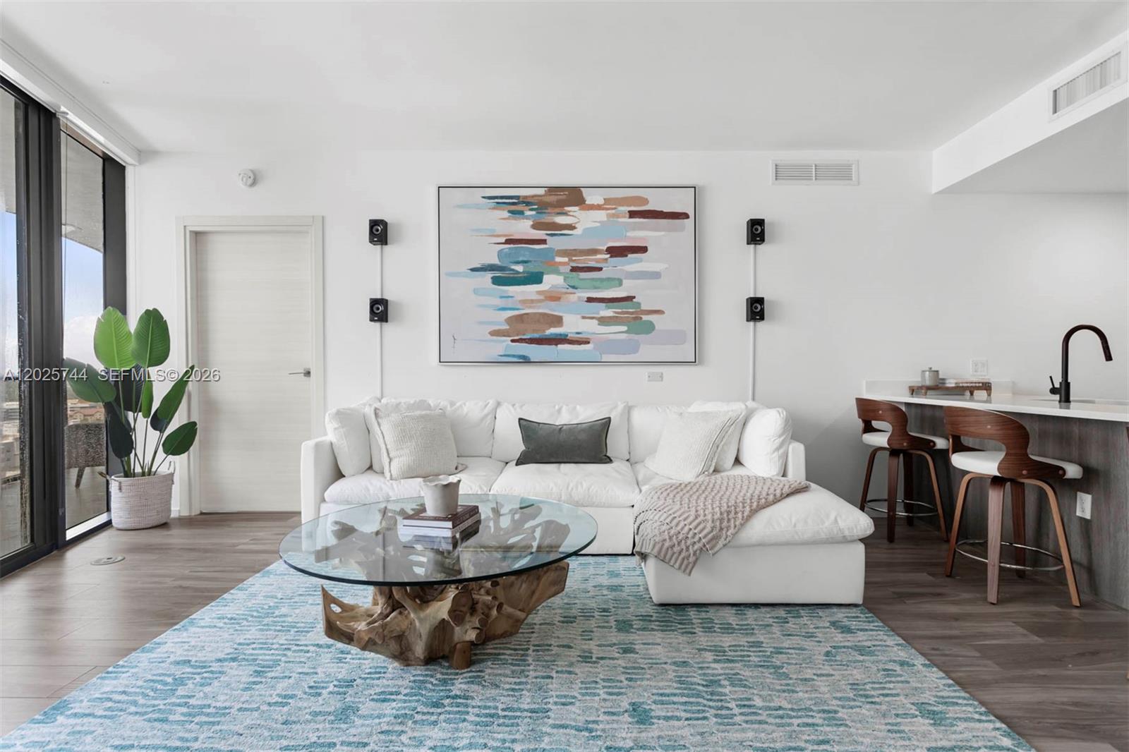 A modern living room features a white sectional sofa, glass coffee table, and city views — 801 S Miami Ave # 2004, Miami FL 33130, MIAMI, FL