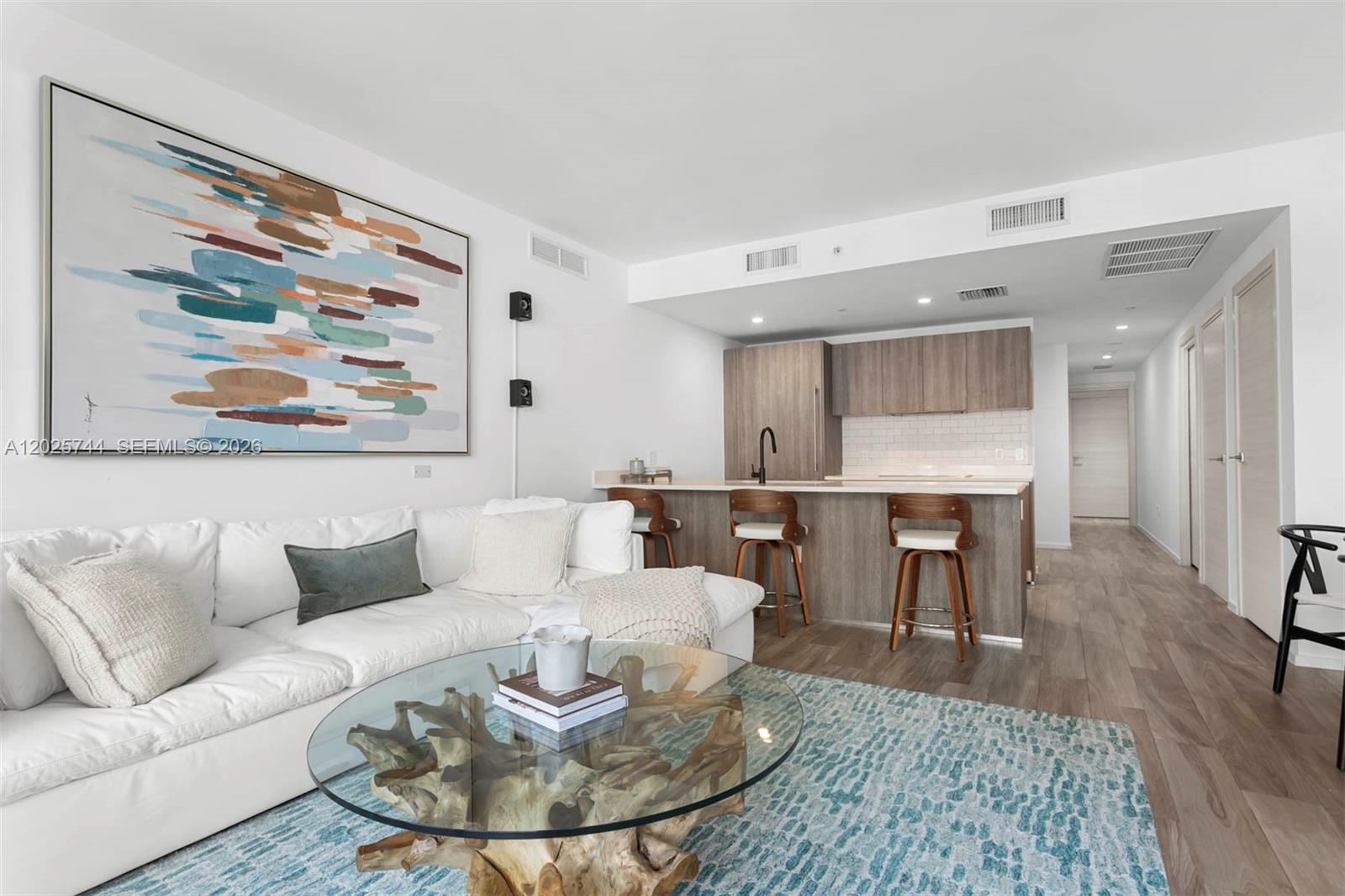 A modern kitchen with wood cabinetry and a breakfast bar opens into a dining area — 801 S Miami Ave # 2004, Miami FL 33130, MIAMI, FL