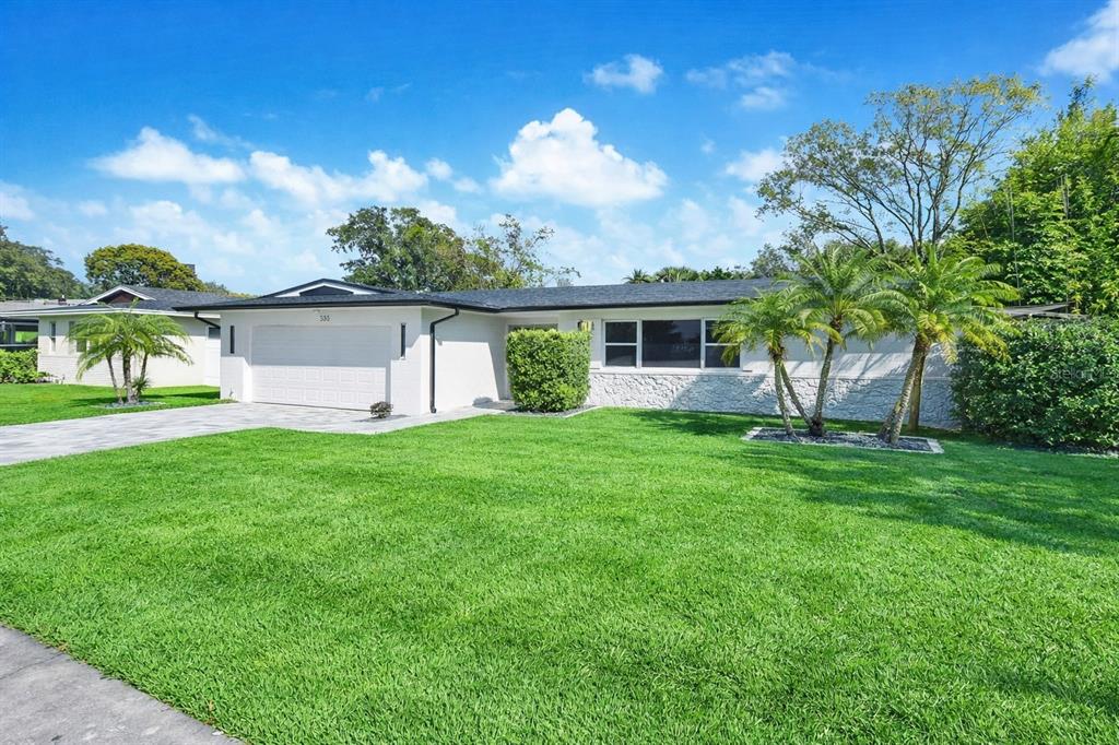 A single-story house with a white exterior, stone facade, and a paved driveway — 330 ELKHORN COURT, WINTER PARK, FL